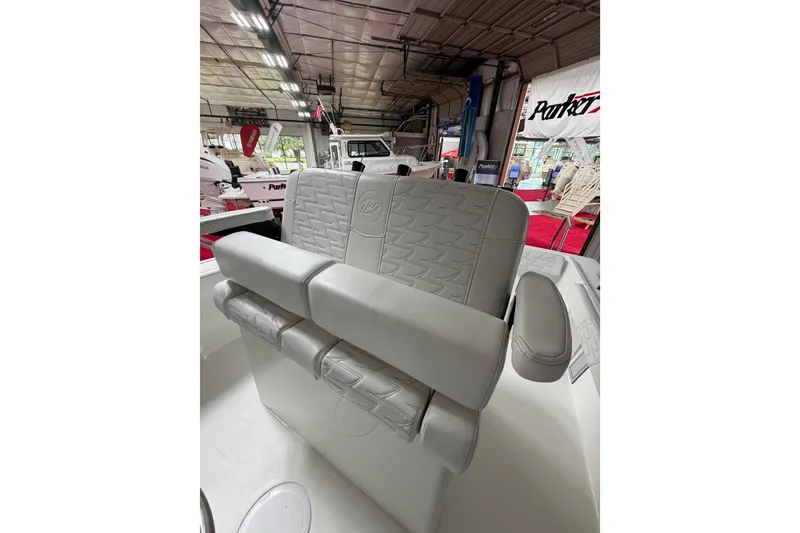 Slide: The Image of 2027 Parker 220 Coastal Elite boat interior with luxurious seating in a showroom. - 12