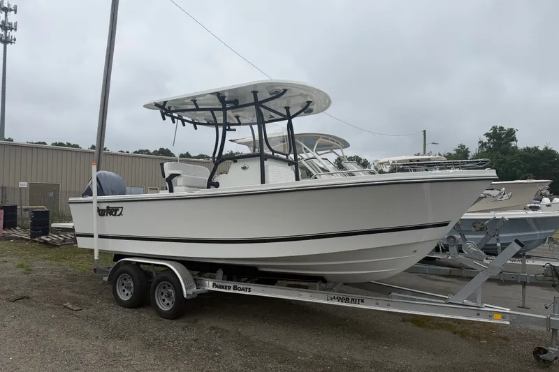 Slide: The Image of 2027 Parker 220 Coastal Elite boat on trailer, parked outdoors on a cloudy day. - 2