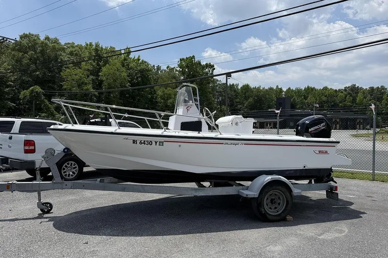The Image of 1996 Boston Whaler Outrage 17 boat on trailer, parked outdoors under a clear sky. - 0
