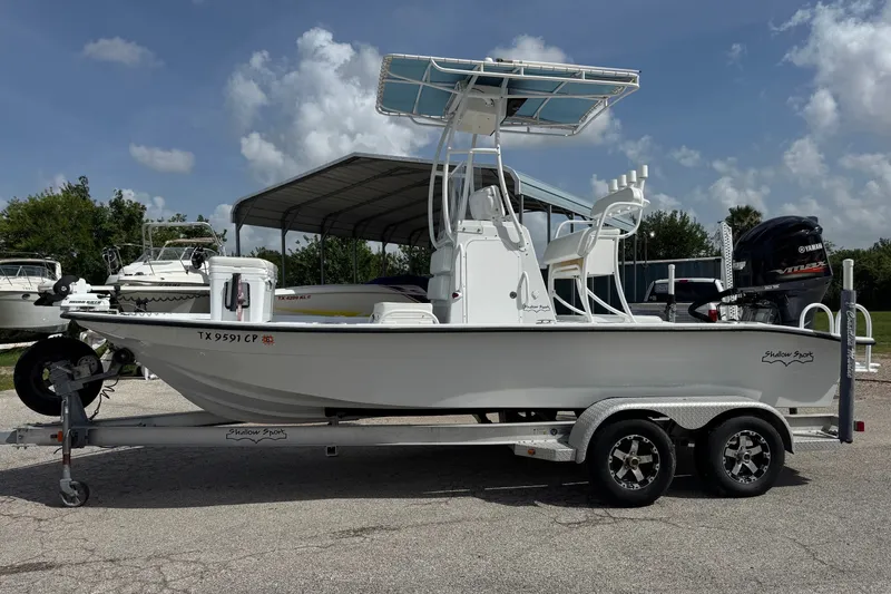 Slide: The Image of 2012 Shallow Sport 21 Modified V boat on trailer, parked outdoors under blue sky. - 1