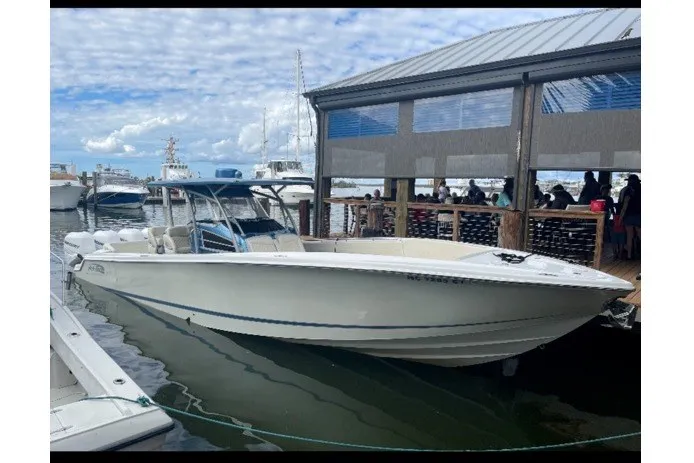 Slide: The Image of 2014 Nor-Tech 390 Sport boat docked near a marina with a covered seating area. - 3