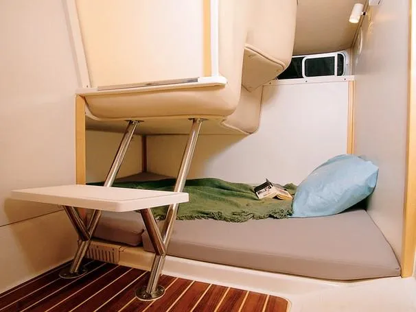 Slide: The Image of The cabin of a 2000 Boston Whaler 28 Conquest with a cozy sleeping area and wooden flooring. - 20