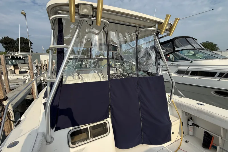 Slide: The Image of 2000 Boston Whaler 28 Conquest boat docked, featuring a covered cockpit area. - 7