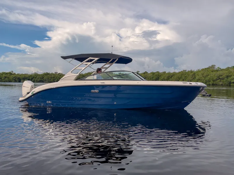 Slide: The Image of Sea Ray SDX 270 Outboard 2027 on calm water with a blue hull and sunshade. - 25