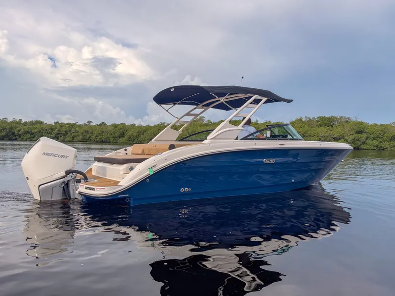 Slide: The Image of A 2027 Sea Ray SDX 270 Outboard on calm water with a blue hull and black canopy. - 2