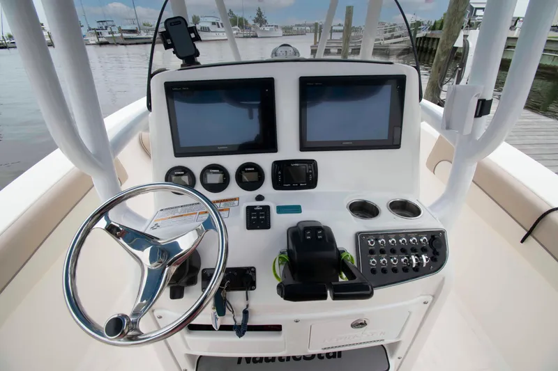 Slide: The Image of 2016 NauticStar 28 XS boat dashboard with dual screens and steering wheel at marina. - 4