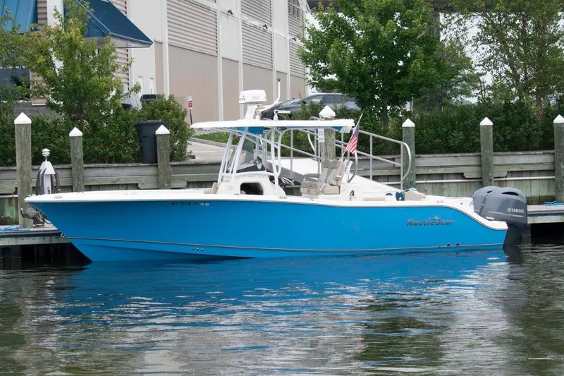 The Image of 2016 NauticStar 28 XS boat docked, featuring a sleek blue hull and Yamaha outboard motor. - 0