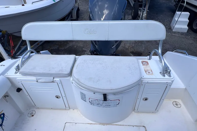Slide: The Image of 2001 Cobia 254 Center Console boat seating and storage area, featuring white cushioned seats. - 10