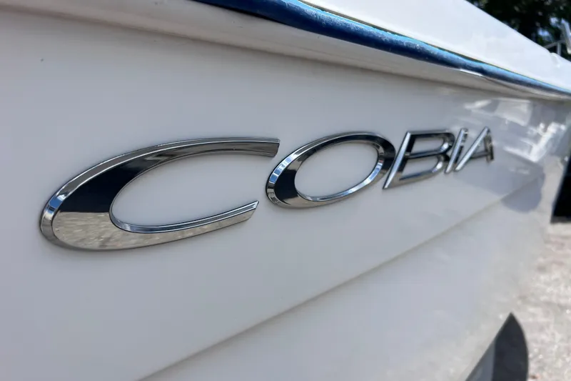 Slide: The Image of 2001 Cobia 254 Center Console boat logo in shiny chrome on white hull. - 4