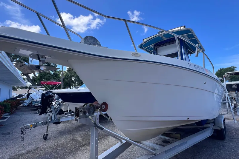 Slide: The Image of 2001 Cobia 254 Center Console boat on trailer under clear blue sky. - 6