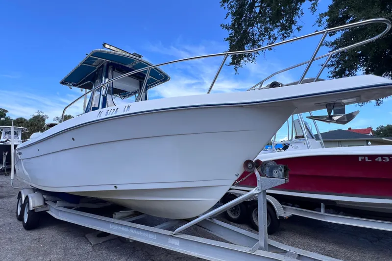 Slide: The Image of 2001 Cobia 254 Center Console boat on trailer, under clear blue sky. - 7