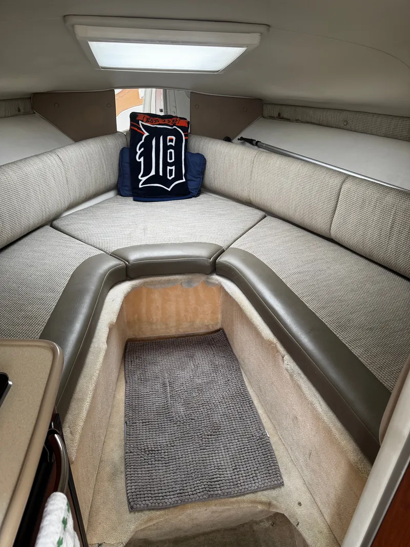 Slide: The Image of The image shows the interior of a 2004 Chaparral Signature 240. There's a U-shaped cushioned seating area with a pillow featuring a "D" logo. The floor is carpeted. - 6