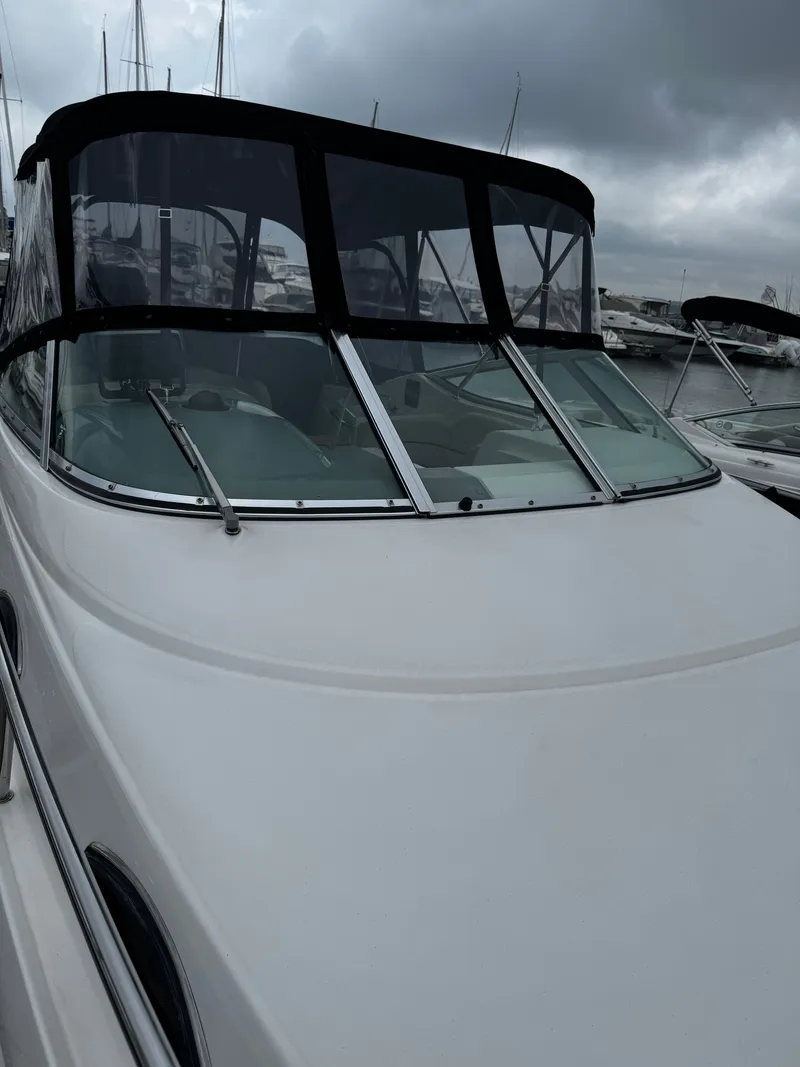 Slide: The Image of A 2004 Chaparral Signature 240 with a black canopy, docked under a cloudy sky. - 1