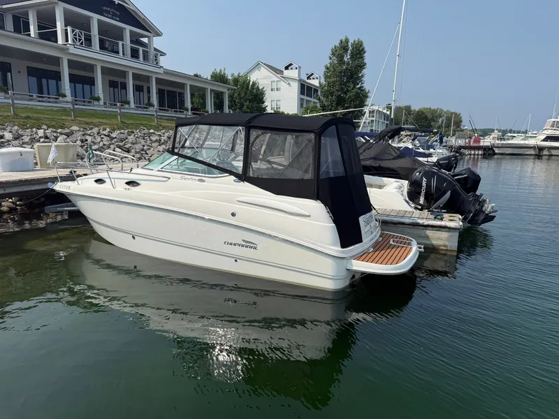 Slide: The Image of A 2004 Chaparral Signature 240 docked in the water. It features a black canopy. - 2