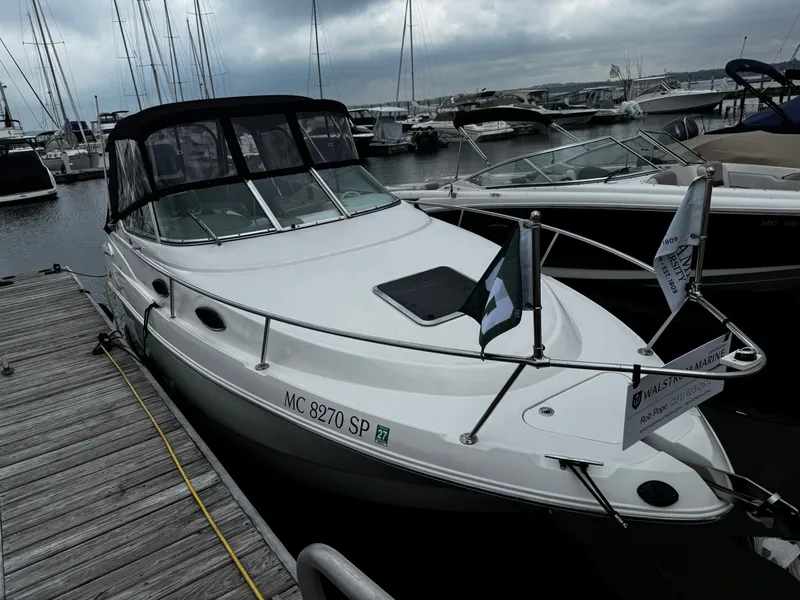 The Image of A 2004 Chaparral Signature 240 docked. It features a black canopy and is surrounded by other boats. - 0
