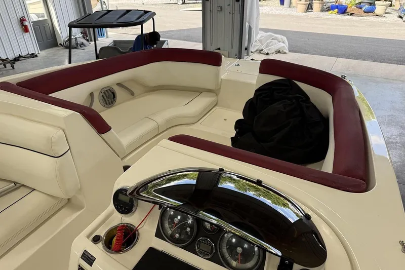 Slide: The Image of 2014 Bayliner 190 Deck Boat interior with red and cream seating, dashboard view. - 3