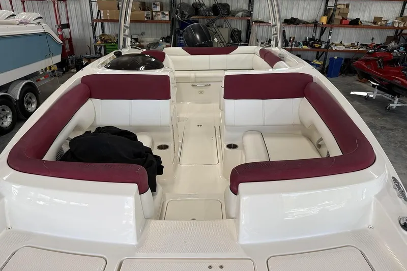 Slide: The Image of 2014 Bayliner 190 Deck Boat interior with maroon and white seating in a garage setting. - 8