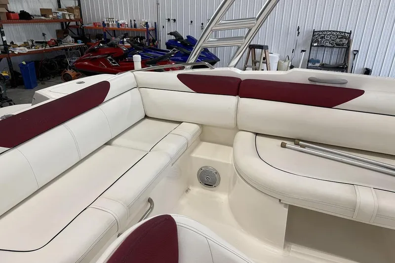 Slide: The Image of 2014 Bayliner 190 Deck Boat interior with white and maroon seating in a garage setting. - 7
