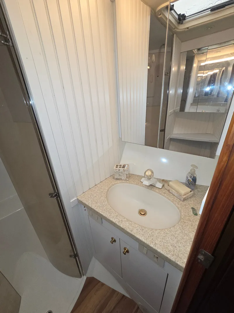 Slide: The Image of A bathroom with a sink, mirror, and shower inside a boat. - 18