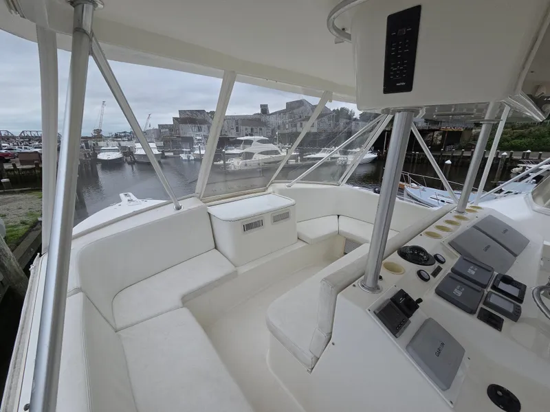 Slide: The Image of The image shows the cockpit of a 2002 Ocean Convertible. It features white seating and a modern helm. A harbor with several boats is visible in the background. - 32