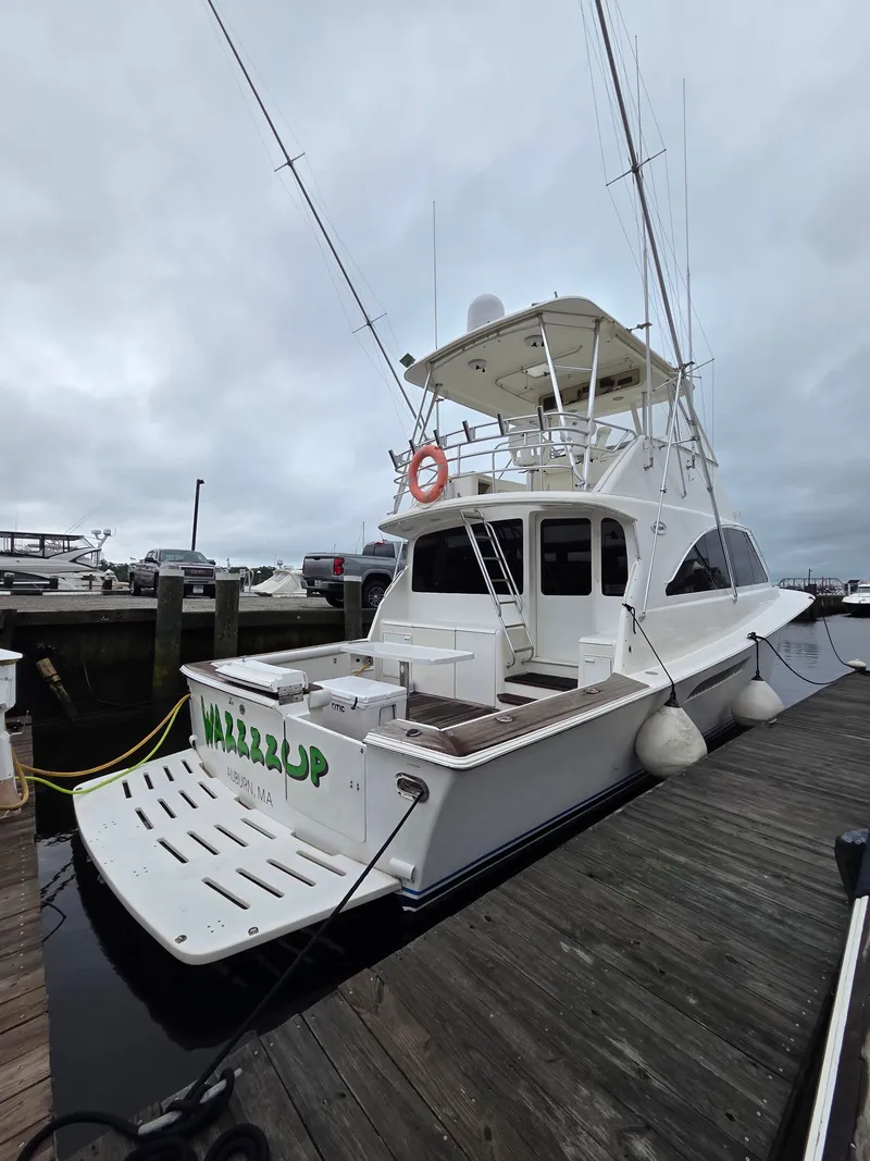 The Image of A white sport fishing boat docked, featuring an elevated helm and multiple fishing rod holders. - 0