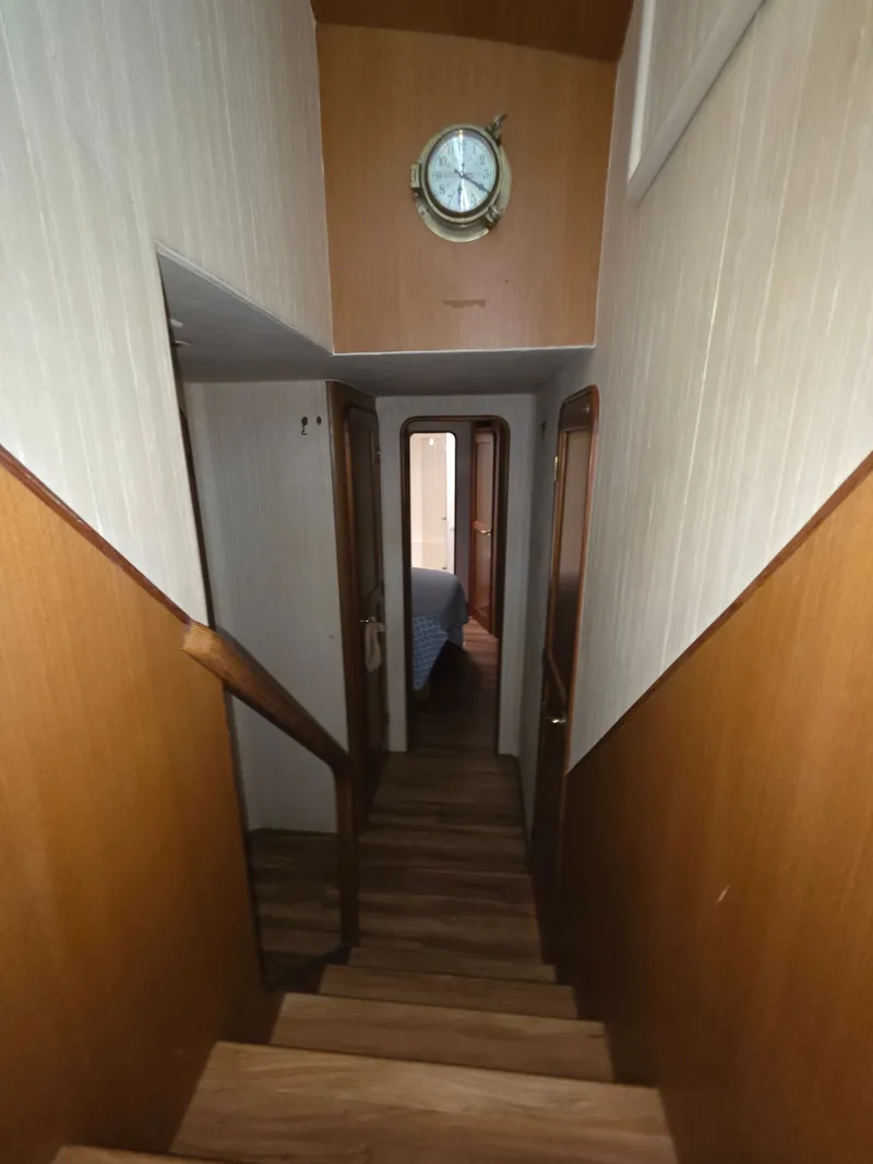 Slide: The Image of A narrow stairway inside a boat with wooden walls and a porthole clock on the wall. - 15