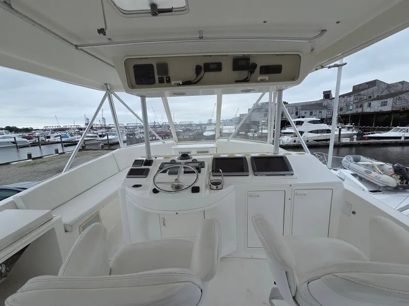 Slide: The Image of Helm of a 2002 Ocean Convertible with two seats, steering wheel, and instruments, docked at a marina. - 30