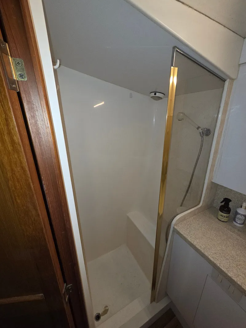 Slide: The Image of A shower stall with a glass door and gold accents in a boat bathroom. - 20