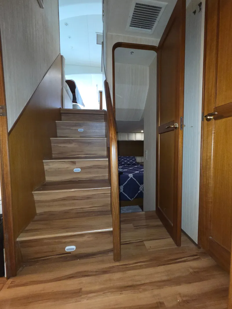 Slide: The Image of Interior view of a yacht with wooden stairs leading to a bedroom with a blue and white bed. - 22