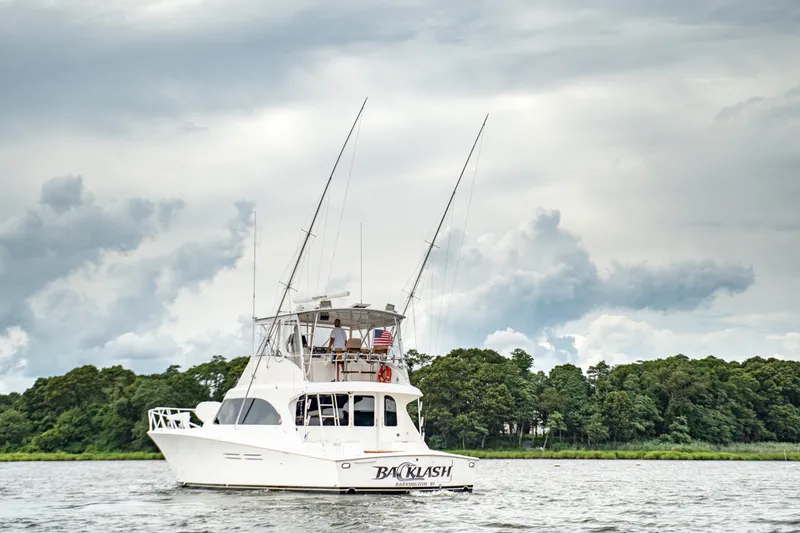 Slide: The Image of 2005 Post 50 Convertible yacht on water, cloudy sky, lush green shoreline in background. - 3