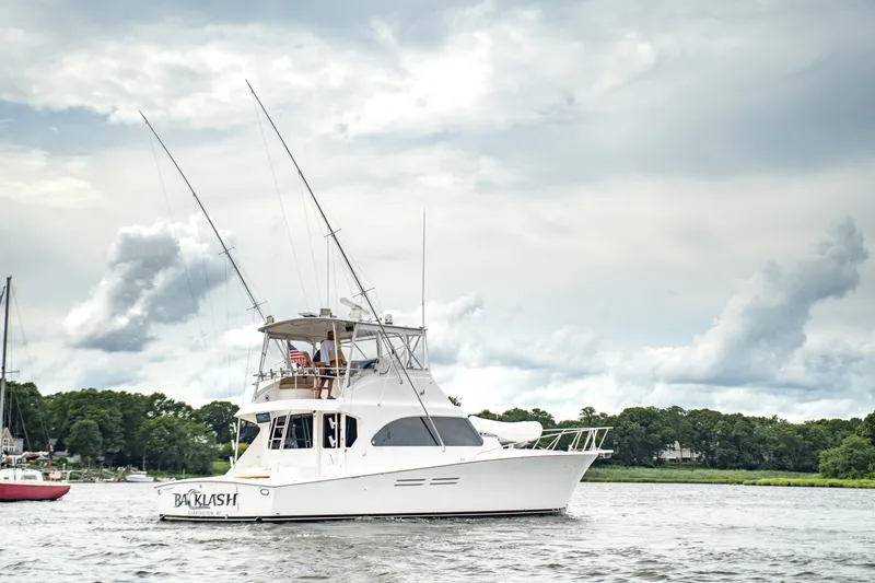 Slide: The Image of 2005 Post 50 Convertible yacht cruising on a scenic waterway under cloudy skies. - 2
