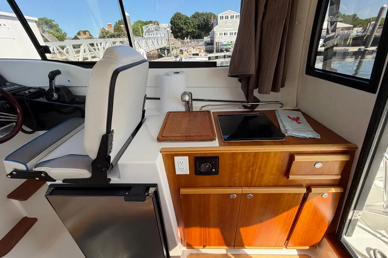 Slide: The Image of Interior of 2017 Cutwater C-242 Coupe featuring helm seat and compact kitchenette. - 10