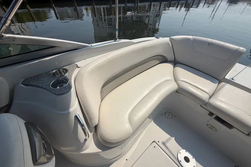 Slide: The Image of 2008 Crownline 240 LS boat interior with beige seating and cup holders, docked by the water. - 26