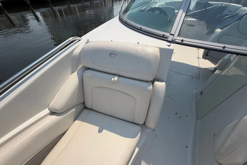 Slide: The Image of 2008 Crownline 240 LS boat interior with white seating and windshield, docked by the water. - 9