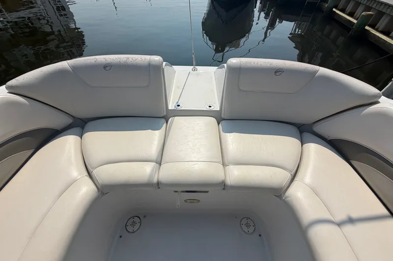 Slide: The Image of 2008 Crownline 240 LS boat interior with white cushioned seating, docked by the water. - 29