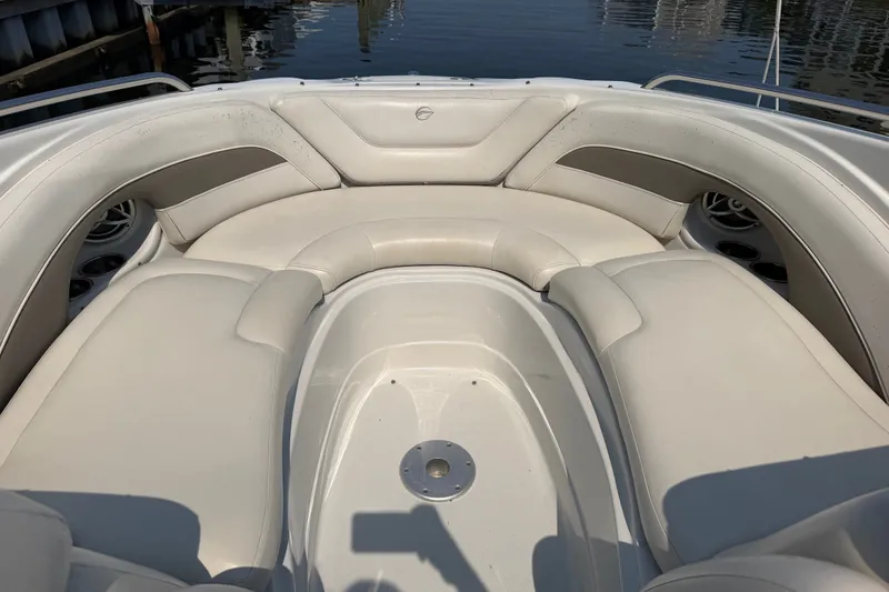 Slide: The Image of 2008 Crownline 240 LS boat interior with plush seating and cup holders, docked by the water. - 8
