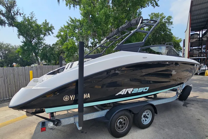 Slide: The Image of 2023 Yamaha Boats AR250 on trailer, sleek design, black and white finish, outdoor setting. - 4