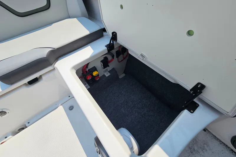 Slide: The Image of 2023 Yamaha Boats AR250 storage compartment with open hatch, showcasing interior space and wiring. - 28