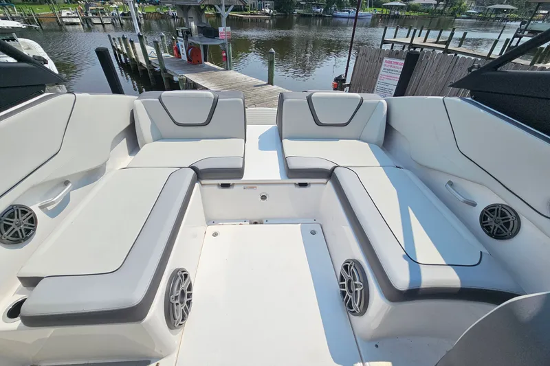 Slide: The Image of 2023 Yamaha Boats AR250 interior with spacious seating and sleek design at a marina. - 25