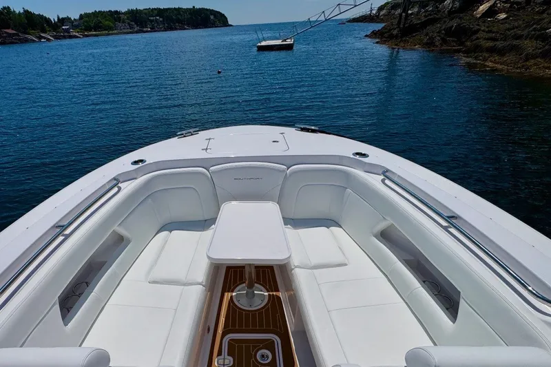 Slide: The Image of 2024 Southport 33 DC boat interior with white seating, wooden table, and scenic water view. - 27