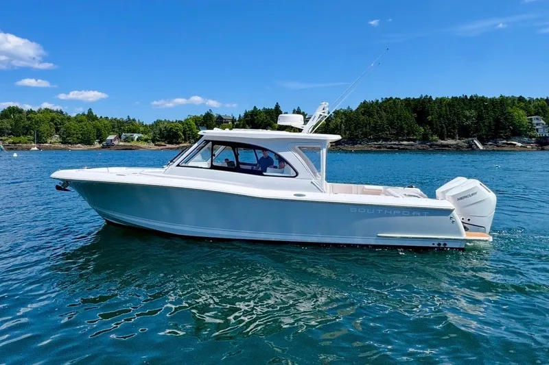 Slide: The Image of 2024 Southport 33 DC boat on clear blue water, scenic forested shoreline in background. - 4