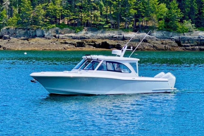 Slide: The Image of 2024 Southport 33 DC boat cruising on a serene lake with forested shoreline. - 2
