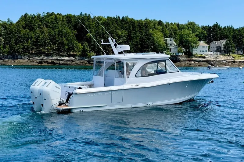Slide: The Image of 2024 Southport 33 DC boat cruising on a serene lake with forested shoreline. - 3