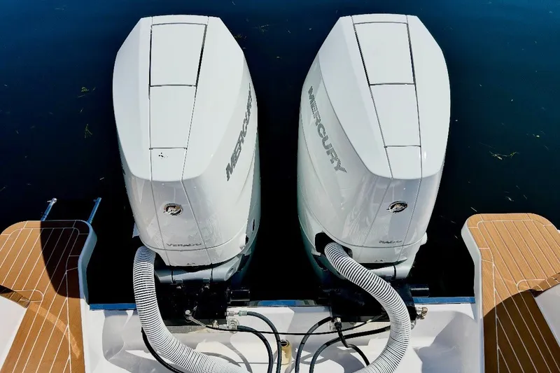 Slide: The Image of Twin Mercury outboard engines on a 2024 Southport 33 DC boat, docked on calm water. - 8