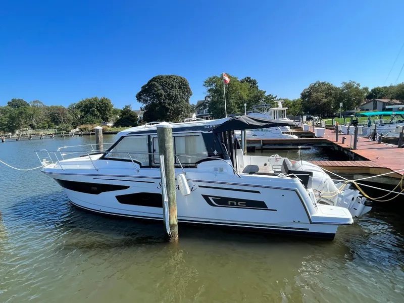 The Image of 2022 Jeanneau NC 1095 boat docked at a marina under clear blue skies. - 0