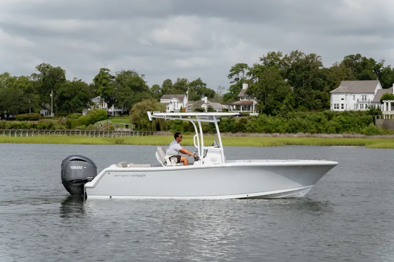Slide: The Image of 2023 Sportsman Heritage 231 Center Console boat on calm water, with scenic shoreline backdrop. - 20