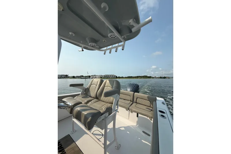 Slide: The Image of 2023 Sportsman Heritage 231 Center Console boat interior with seating and rod holders on a sunny day. - 10