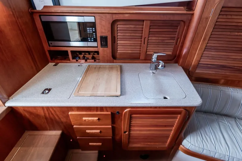 Slide: The Image of Compact galley kitchen in 2012 Hinckley Picnic Boat MKIII with microwave, sink, and wooden cabinetry. - 18