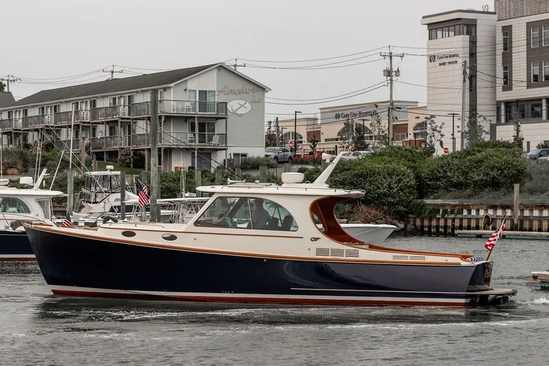 Slide: The Image of A 2012 Hinckley Picnic Boat MKIII cruising on a waterway. Buildings are visible in the background. - 5
