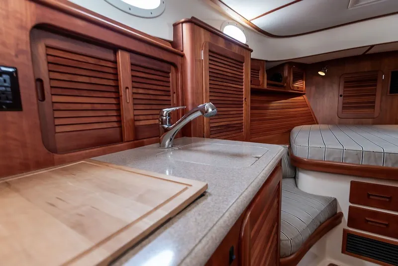 Slide: The Image of Luxurious 2012 Hinckley Picnic Boat MKIII interior with wooden cabinetry and cozy sleeping area. - 16